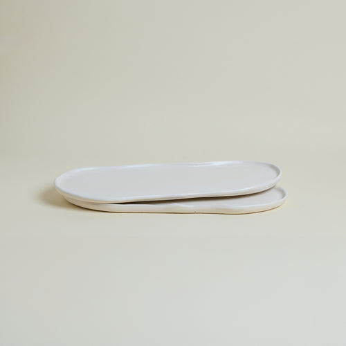Two white ceramic plates stacked on a beige background