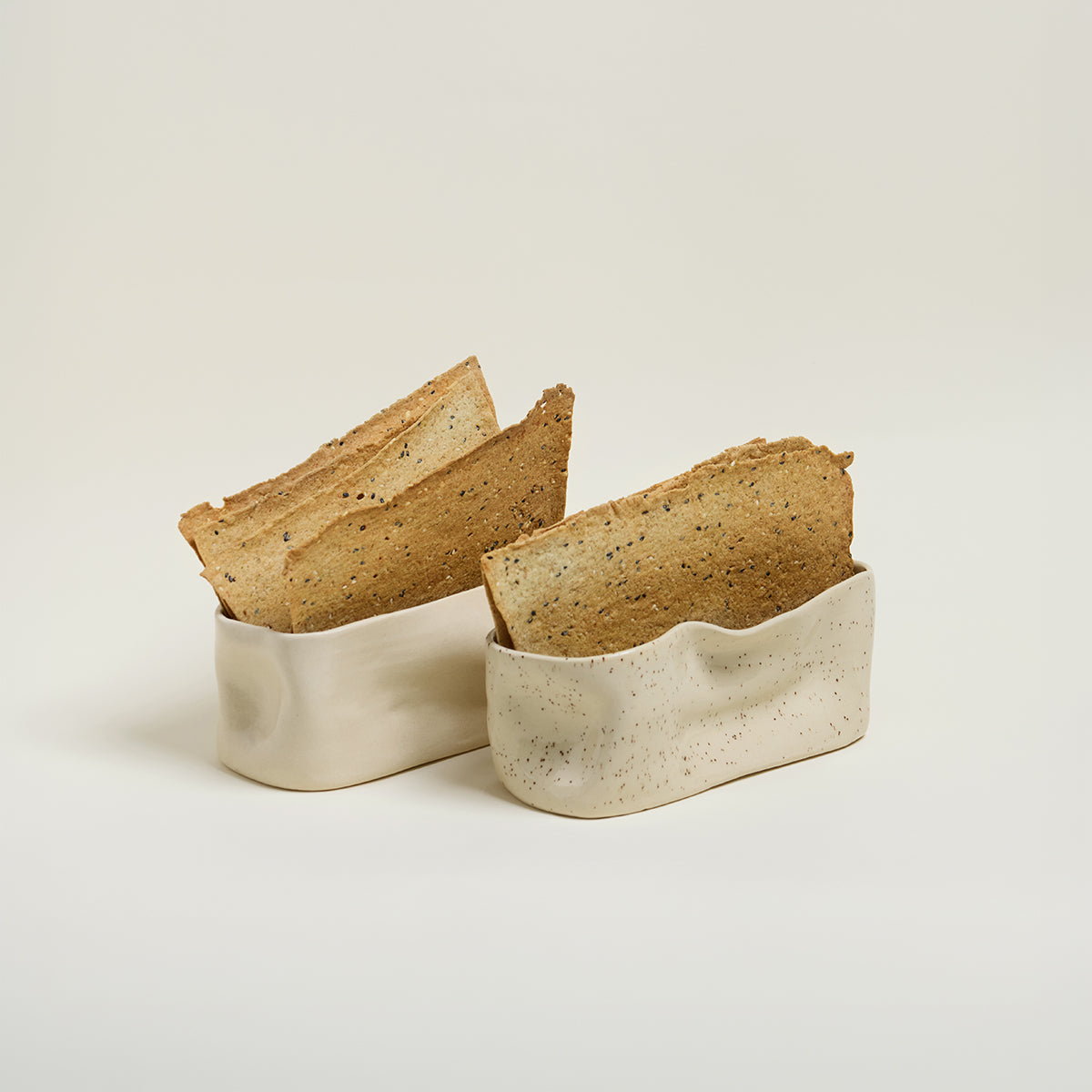 Two pieces of bread in a ceramic container on a light background