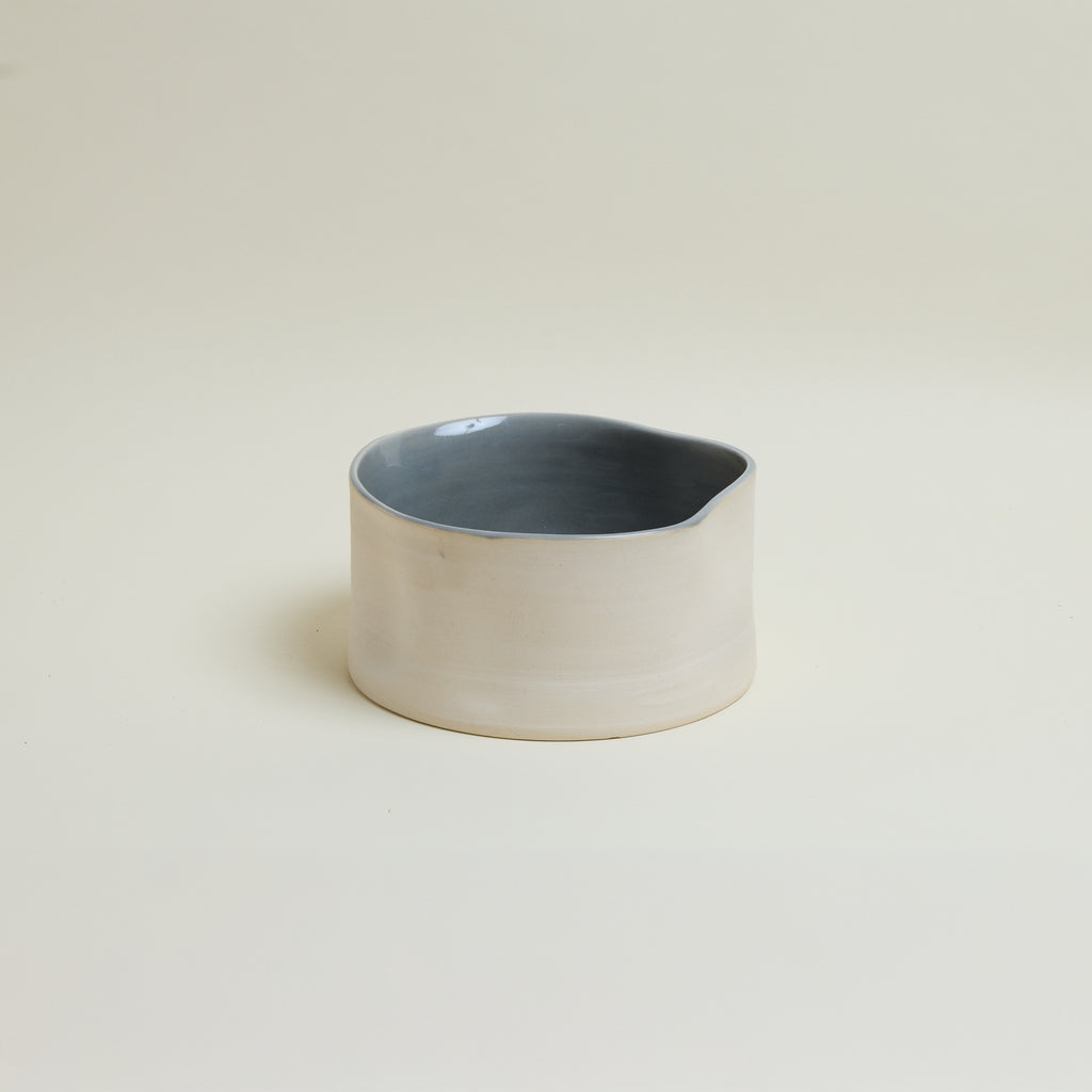 Ceramic container with a blue interior on a beige background