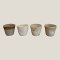 Four ceramic cups with gradient finishes on a light gray background