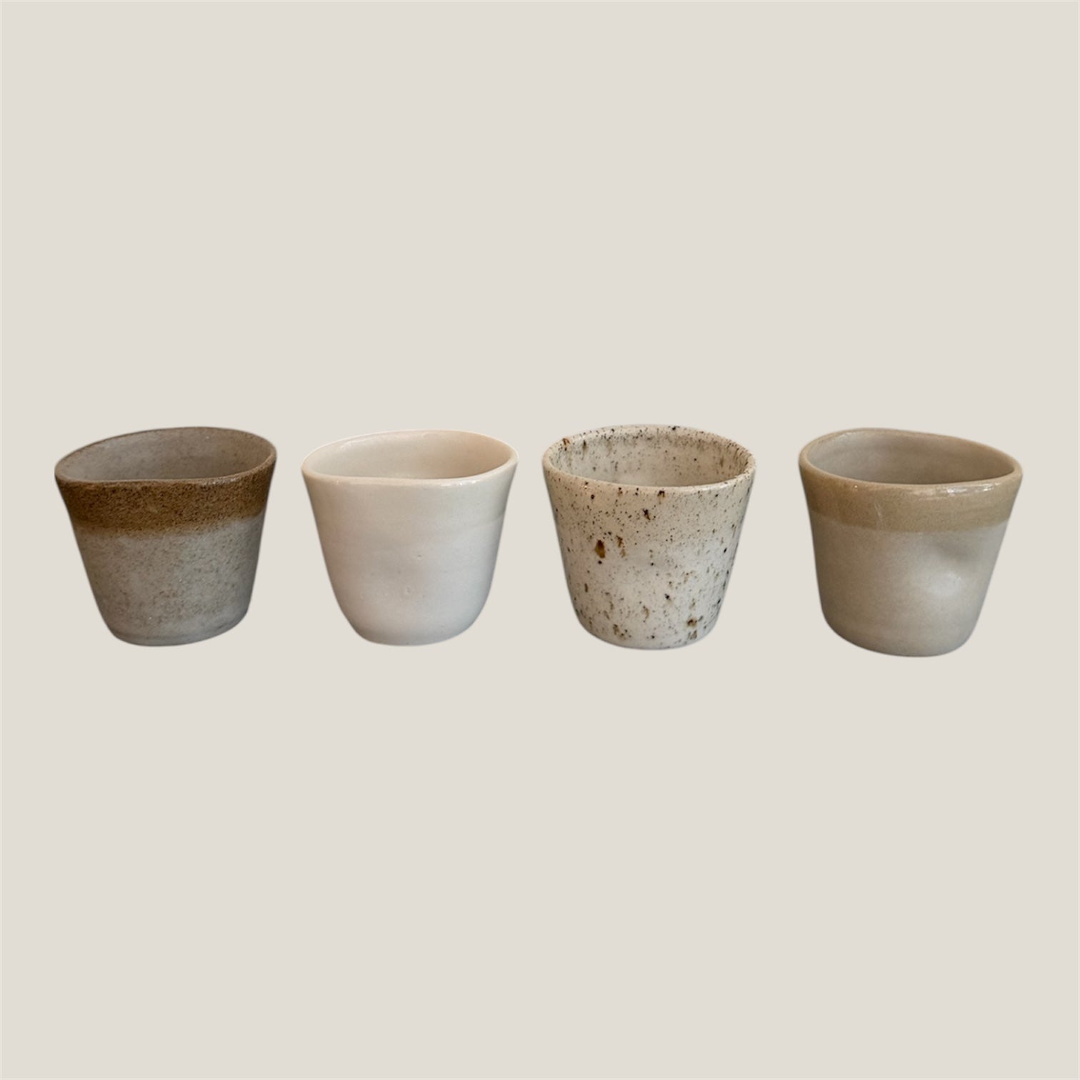 Four ceramic cups with gradient finishes on a light gray background