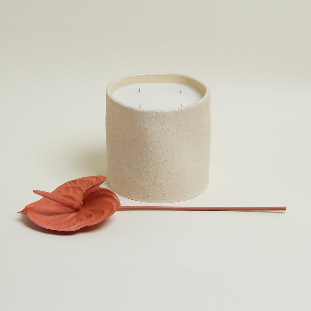 Beige candle with a red flower on a light beige background