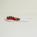 White oval plate with cherry tomatoes on a light beige background