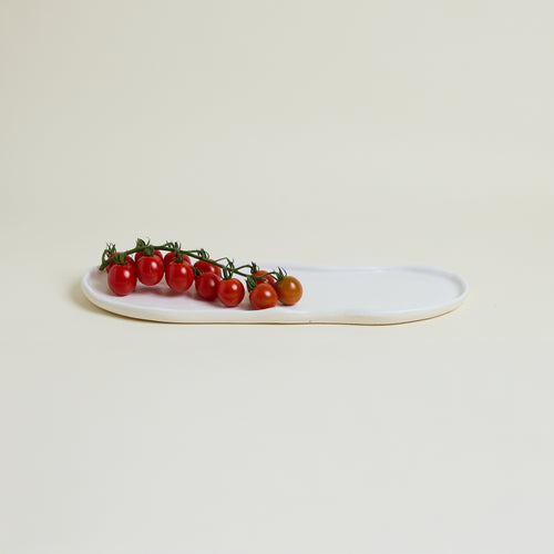 White oval plate with cherry tomatoes on a light beige background